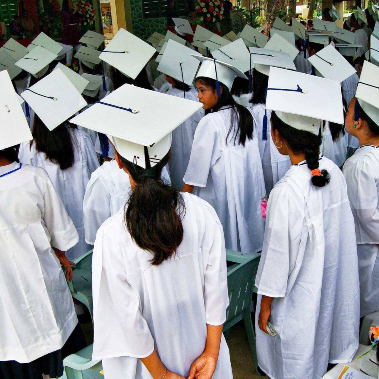 A diverse group of graduates wearing caps and gowns, celebrating their achievement with smiles and excitement.