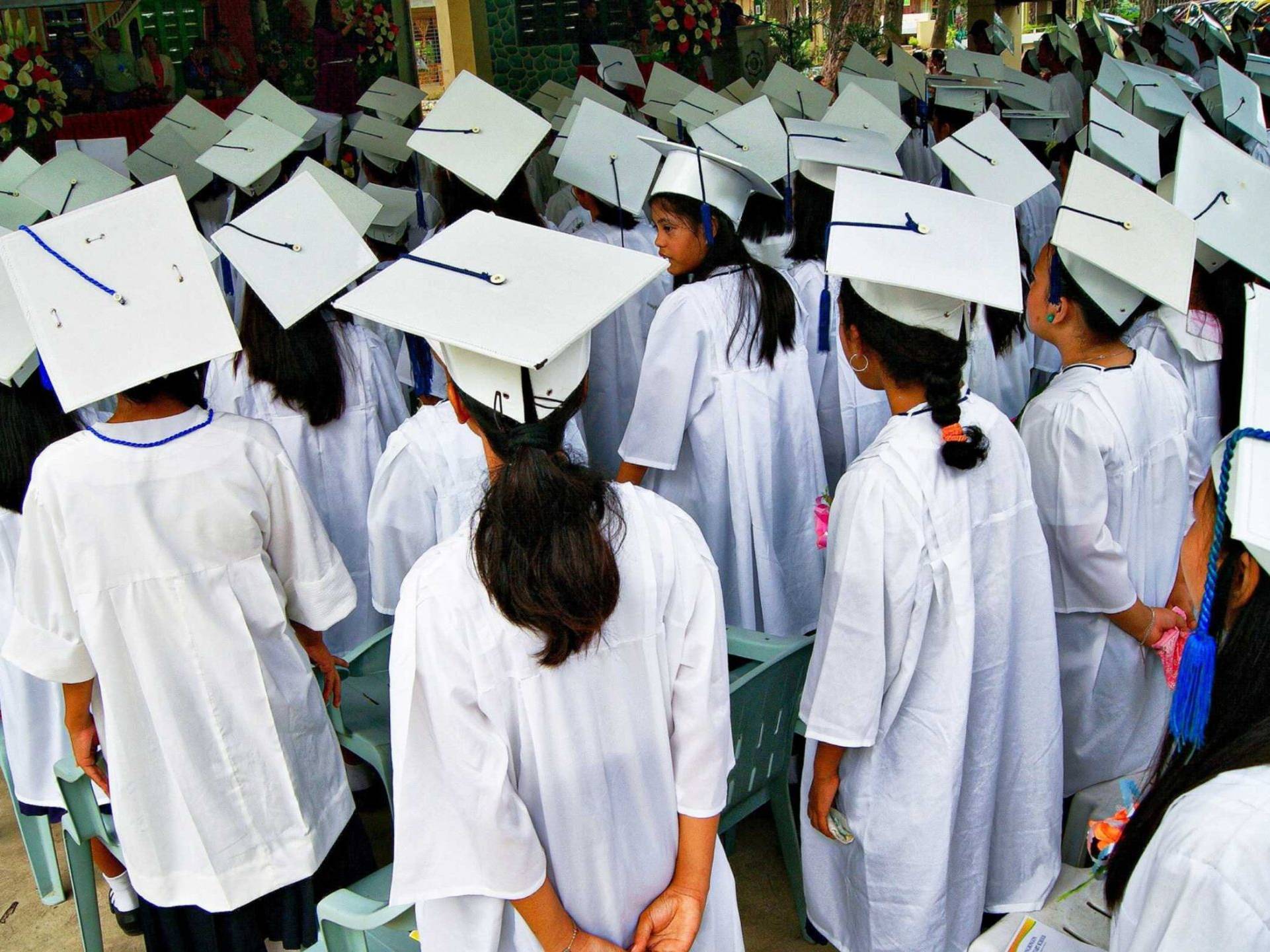 A diverse group of graduates wearing caps and gowns, celebrating their achievement with smiles and excitement.