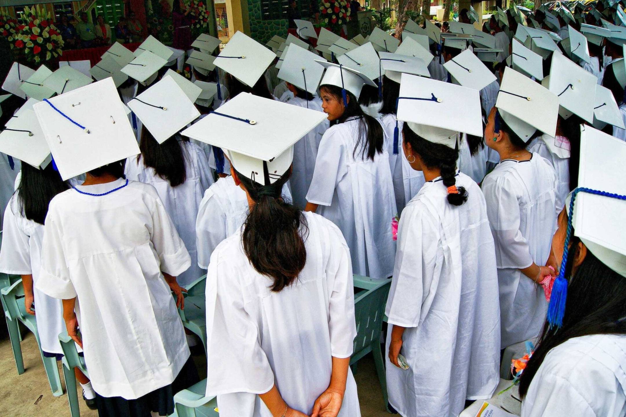 A diverse group of graduates wearing caps and gowns, celebrating their achievement with smiles and excitement.