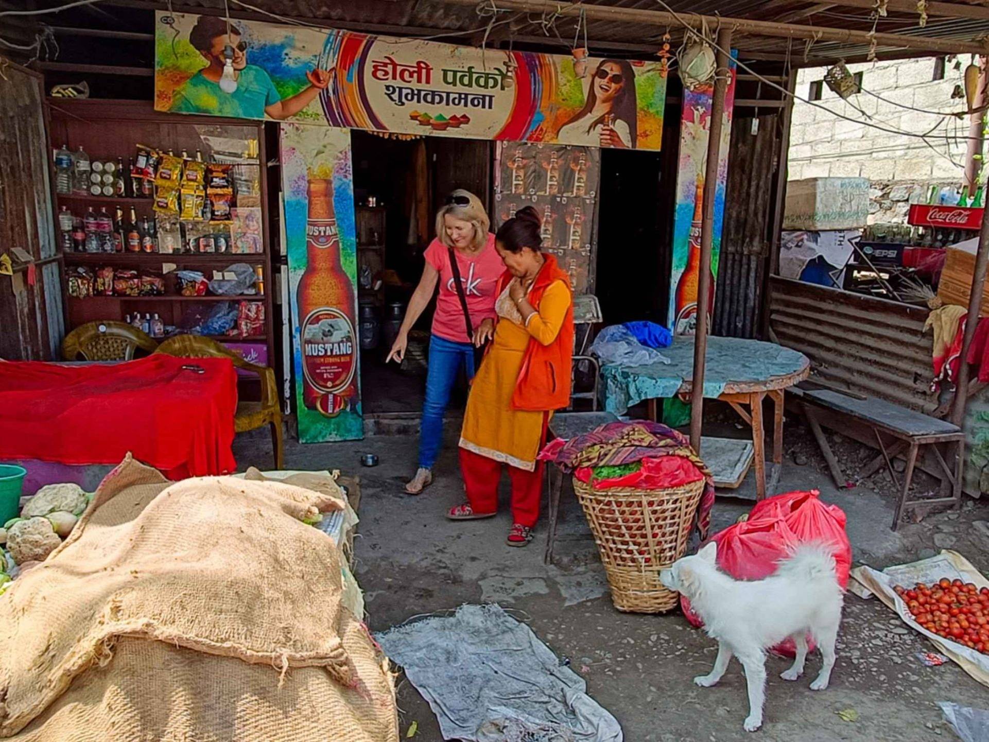 Two women and a dog are positioned outside a quaint shop, creating a friendly and inviting scene.