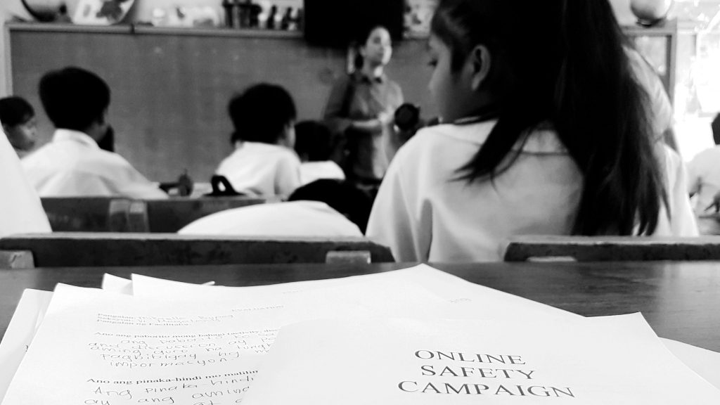 Black and white photo of a classroom filled with children attentively sitting at their desks.