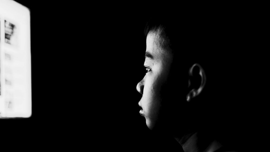 A child gazes intently at a computer screen, focused on the content displayed.