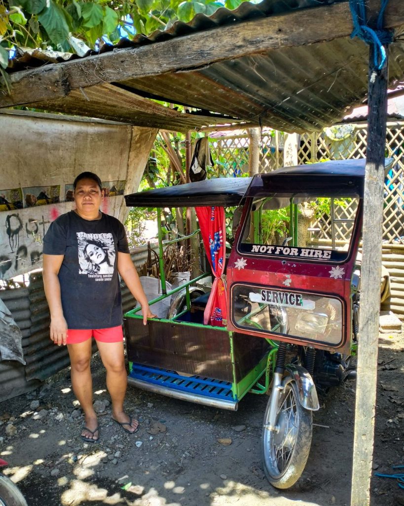 A woman stands beside a Philippine tricycle.