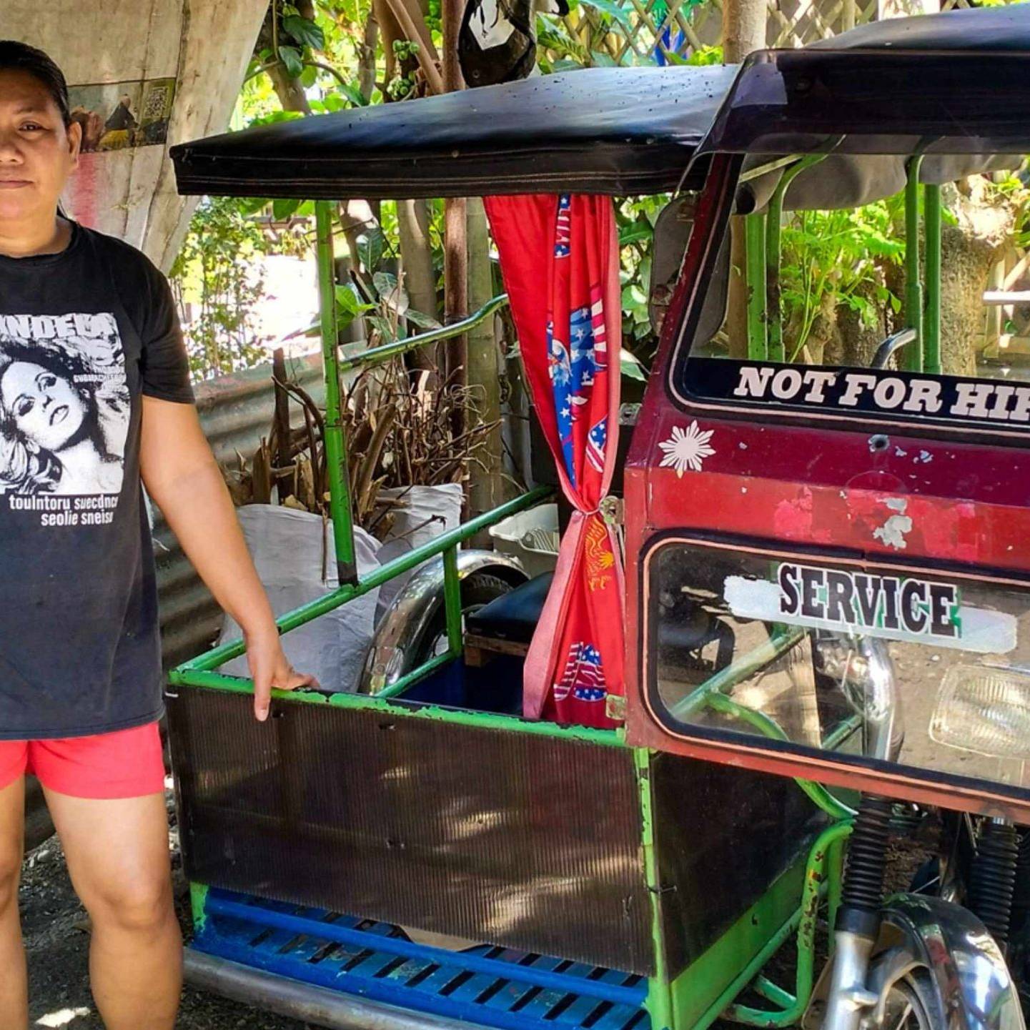 A woman stands beside a Philippine tricycle.