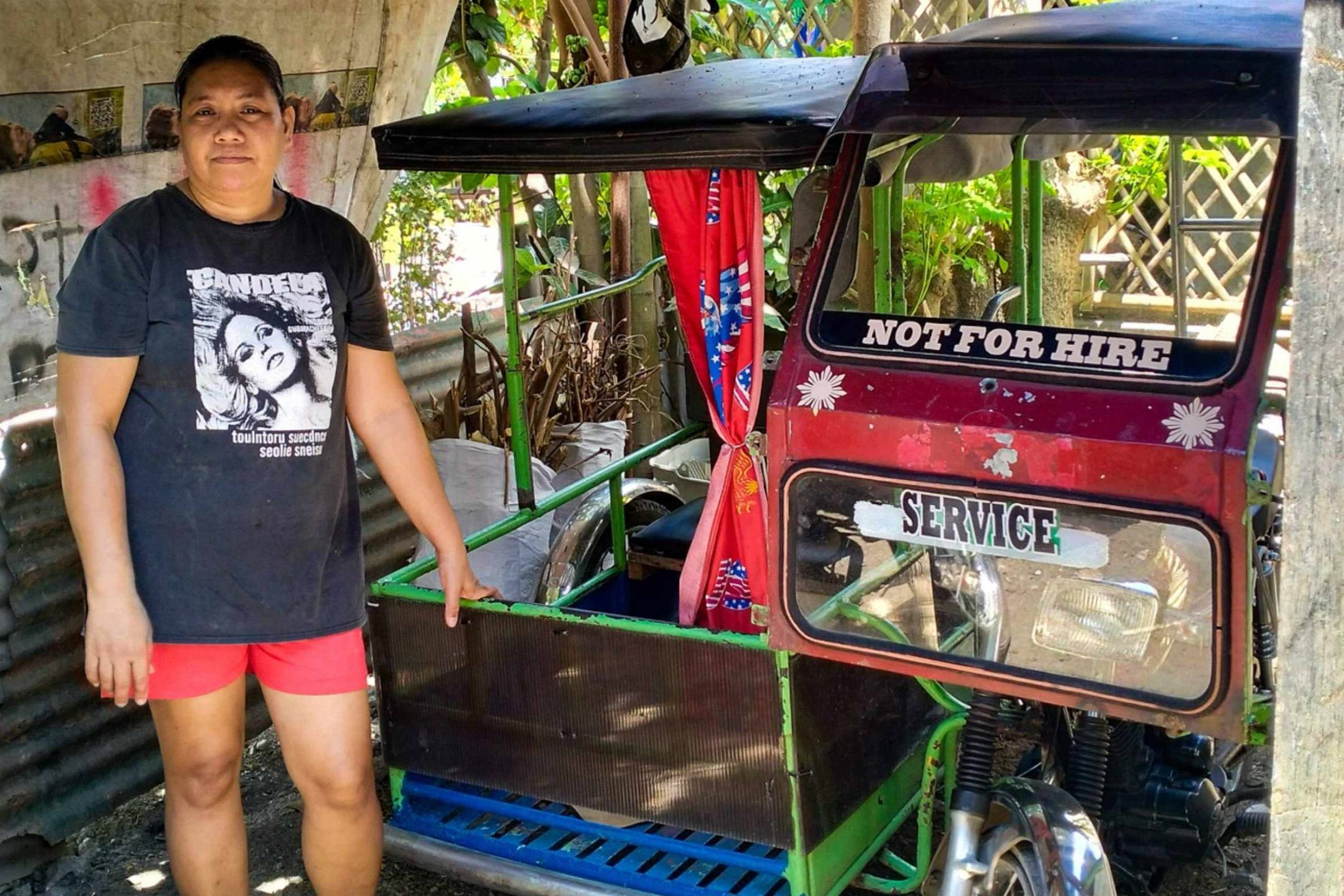 A woman stands beside a Philippine tricycle.