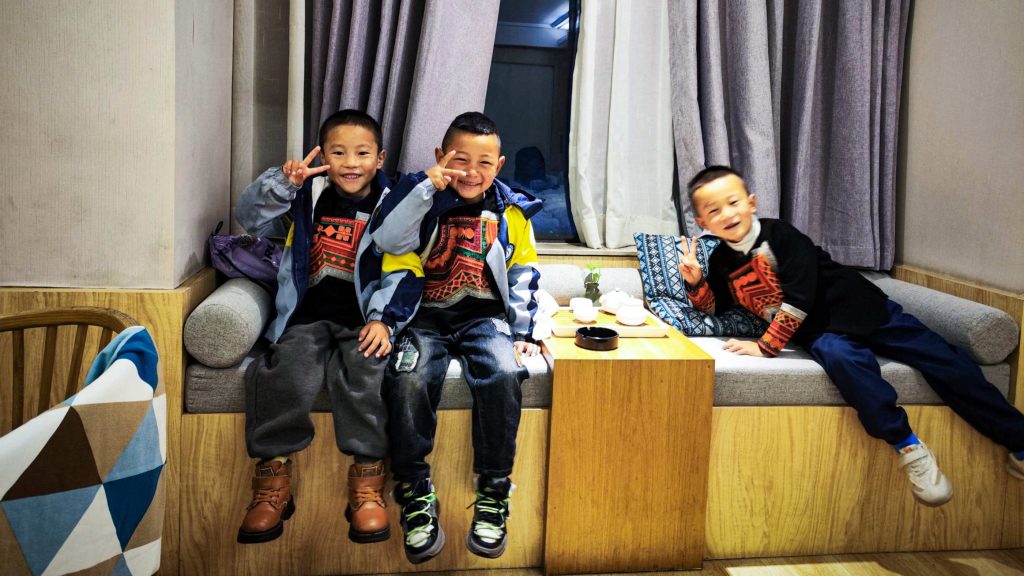 Three boys sitting together on a couch, engaged in conversation and enjoying each other's company.
