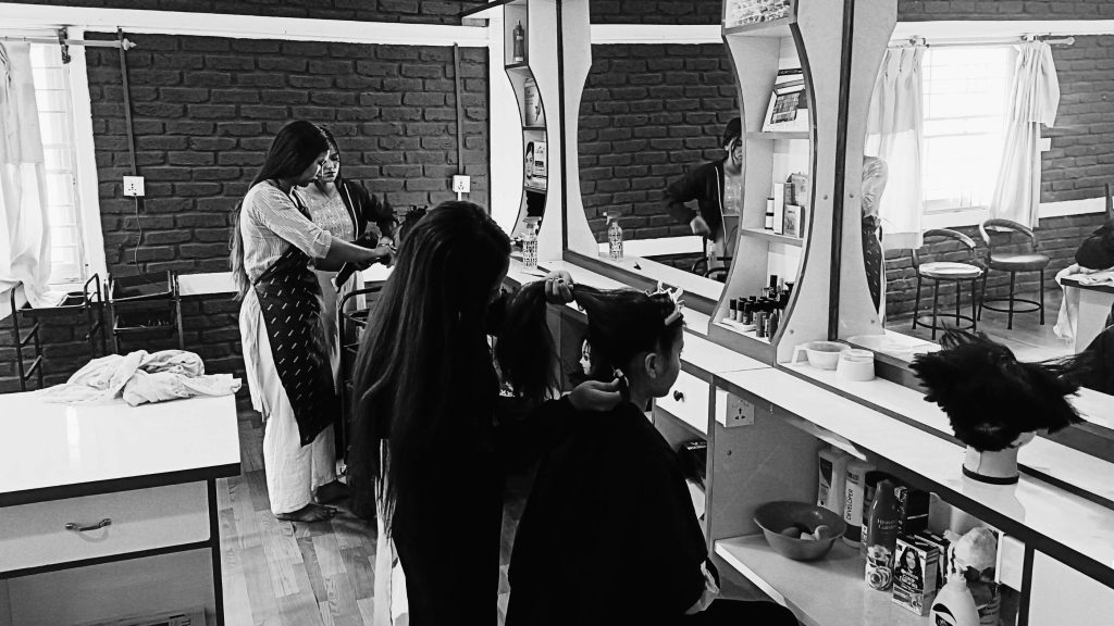 In a salon, a woman is having her hair styled as cosmetology students watch and gain practical experience.
