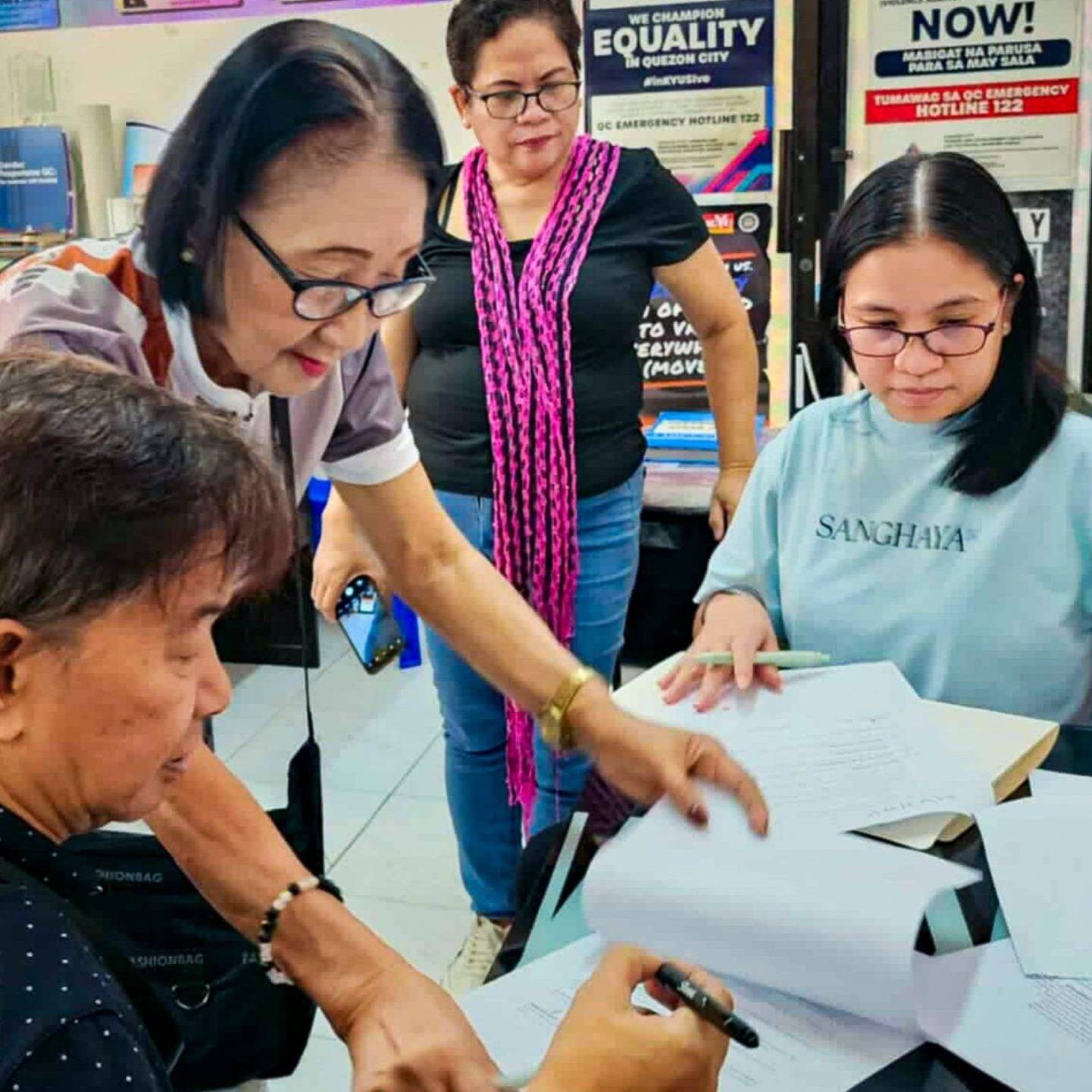 A group of people gathered around a table, reviewing documents and discussing their contents.