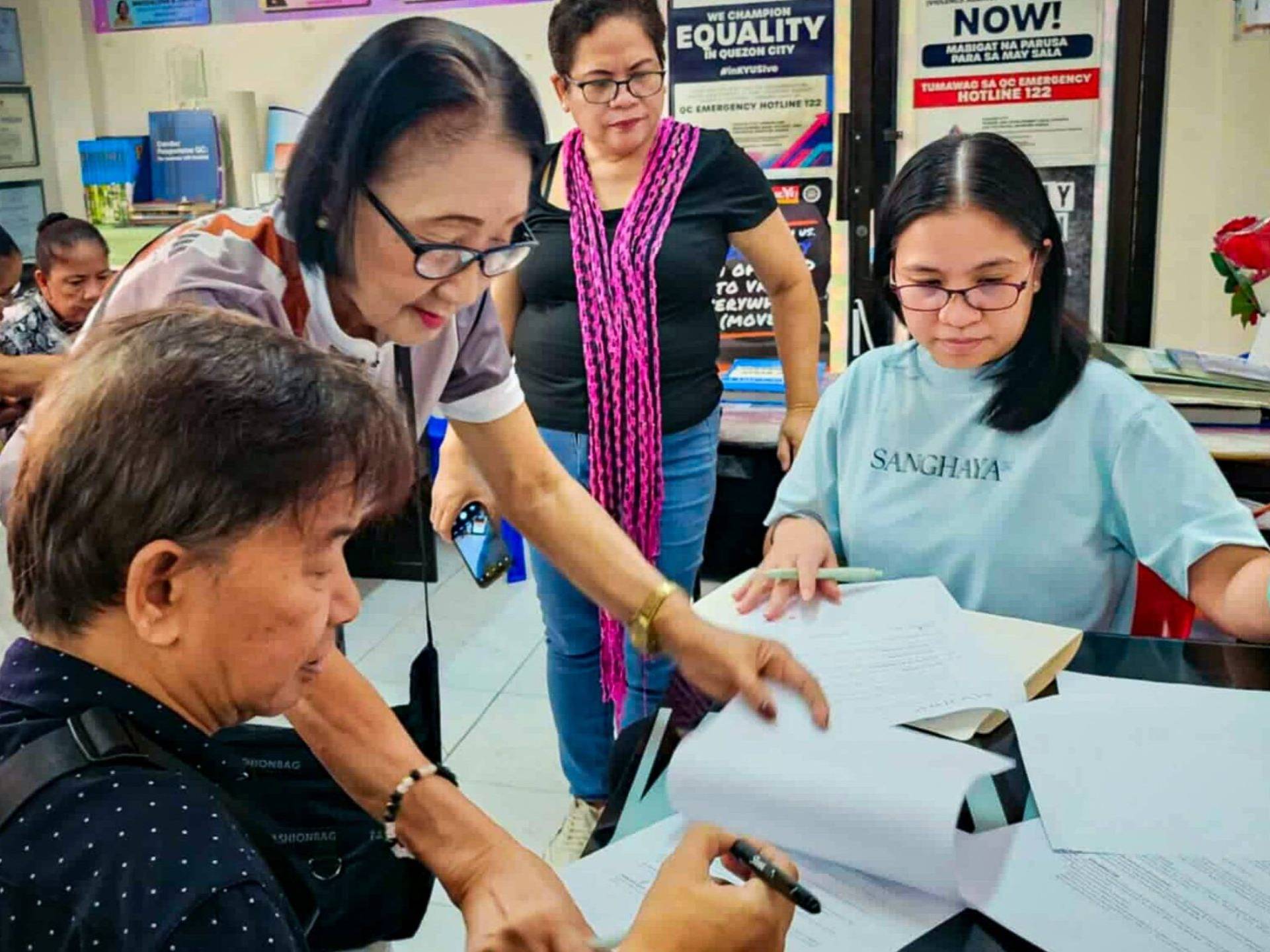 A group of people gathered around a table, reviewing documents and discussing their contents.