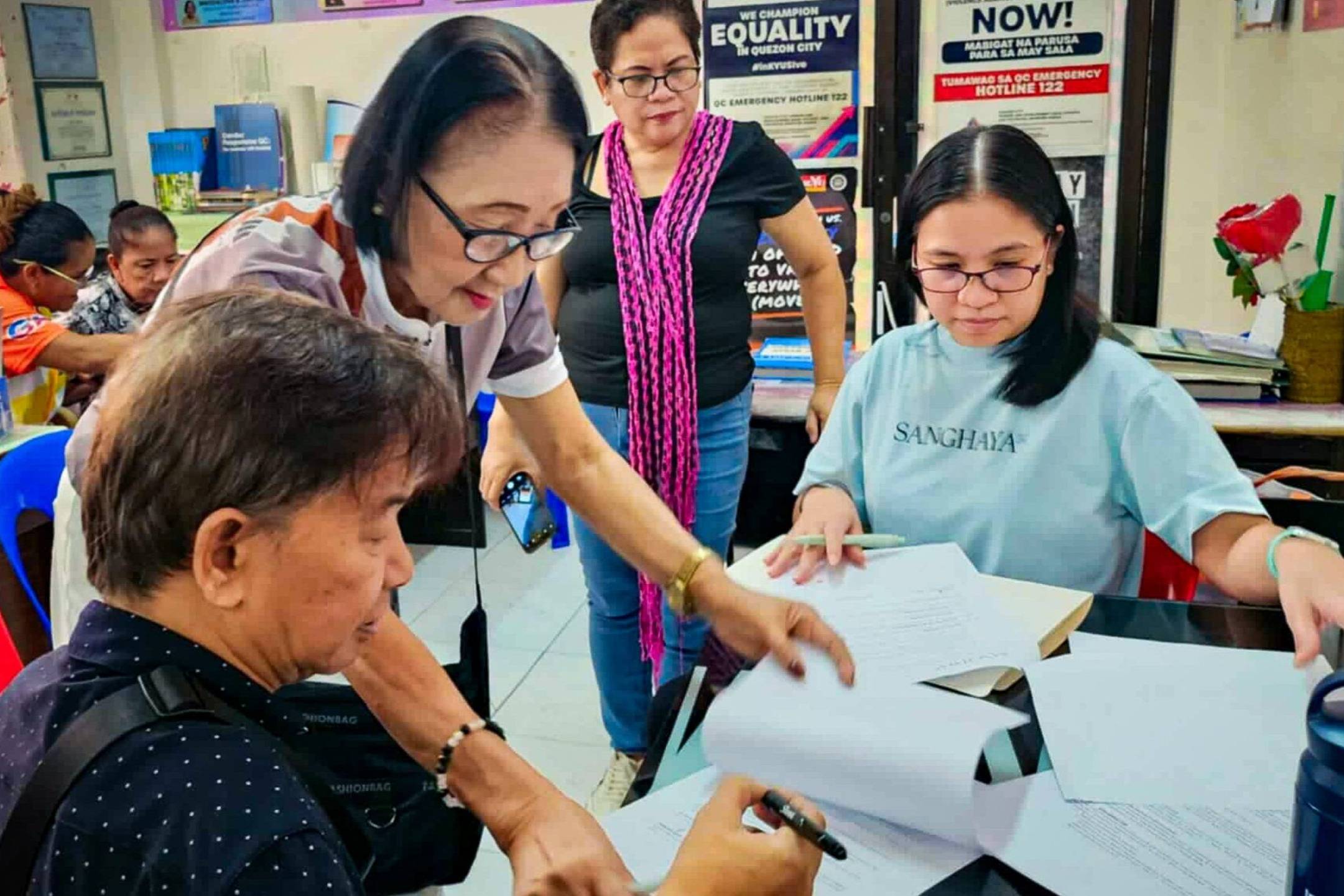 A group of people gathered around a table, reviewing documents and discussing their contents.