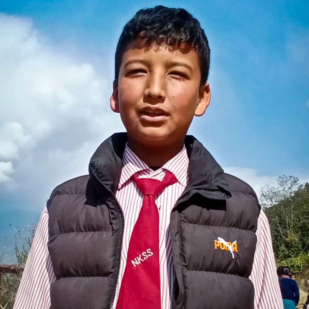 A young person stands outdoors wearing a striped shirt, red tie, and black vest. The sky is partly cloudy, and trees are in the background, creating a serene atmosphere.