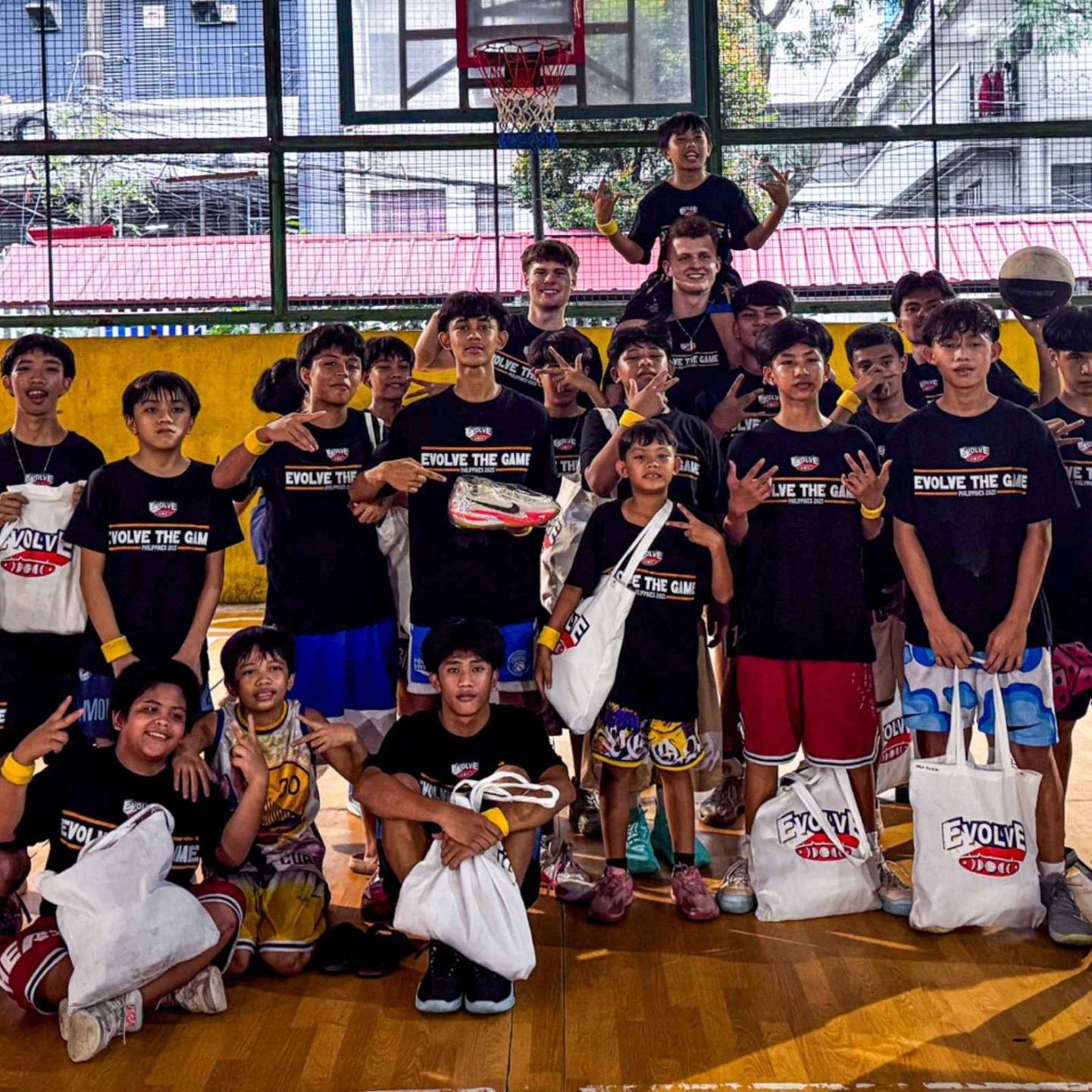 A group of young basketball players on an indoor court, wearing black 