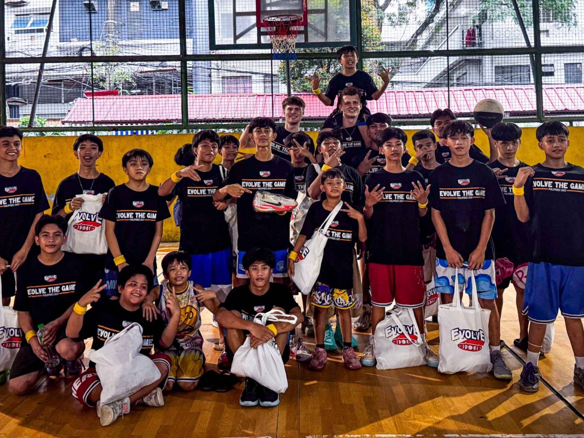 A group of young basketball players on an indoor court, wearing black 