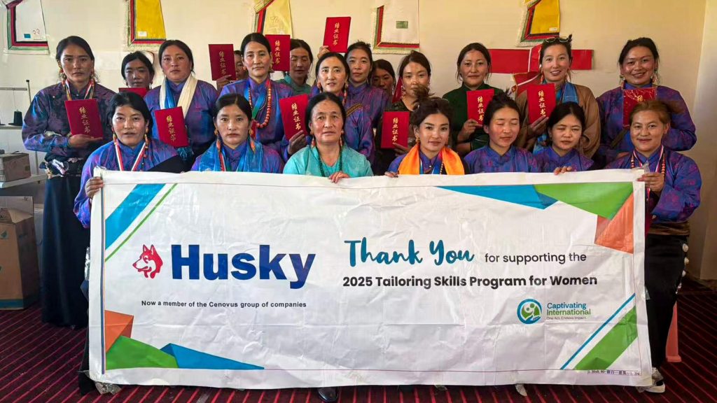 A group of women in traditional attire proudly hold certificates, standing together. They display a banner reading, "Thank you for supporting the 2025 Tailoring Skills Program for Women." The mood is celebratory and empowering.