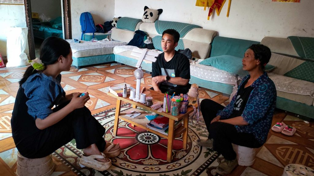 Three people sit around a small table with beauty products in a cozy living room. The tone is relaxed and conversational.