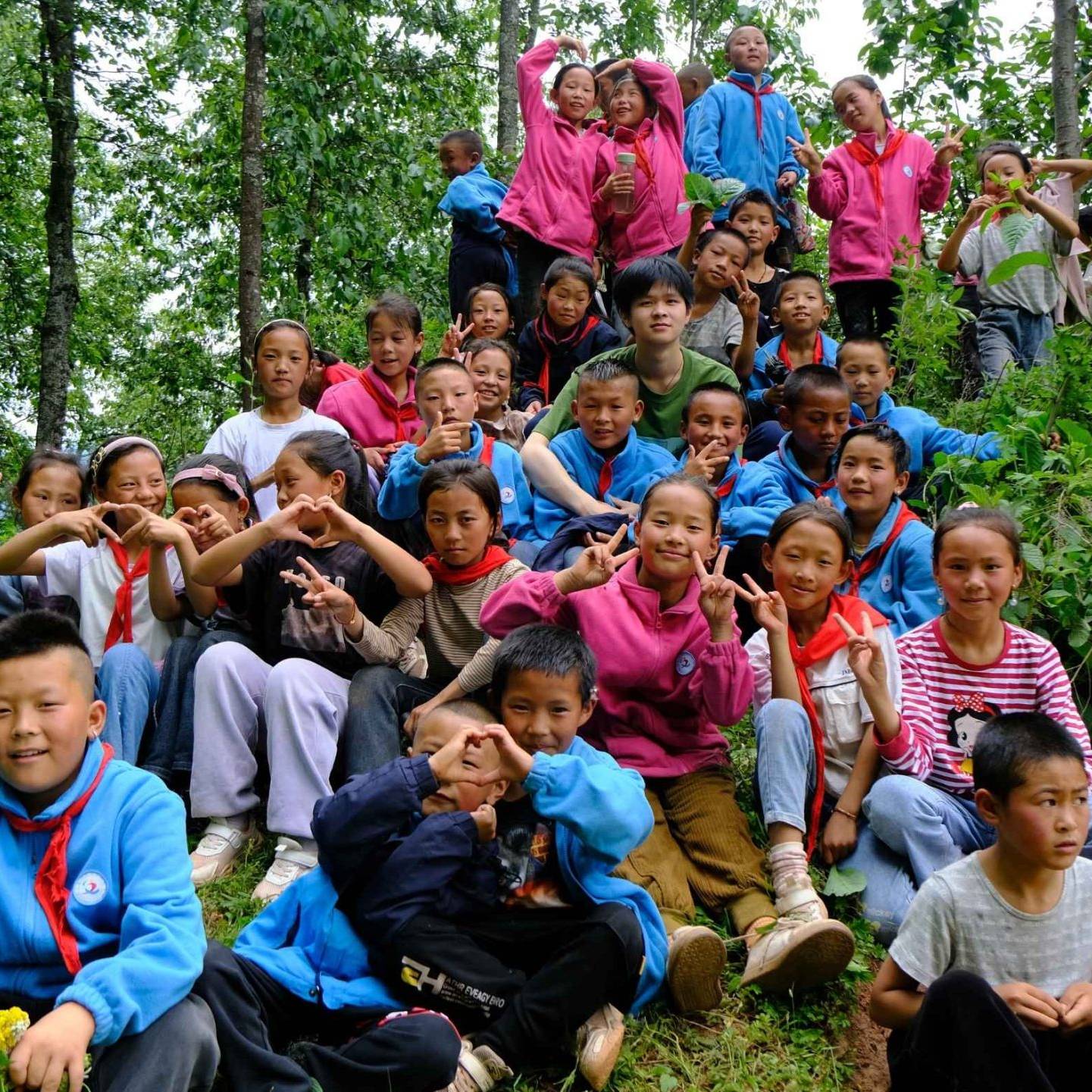 A group of children in colorful clothing pose playfully in a lush forest. The scene conveys joy and camaraderie among the vibrant greenery.