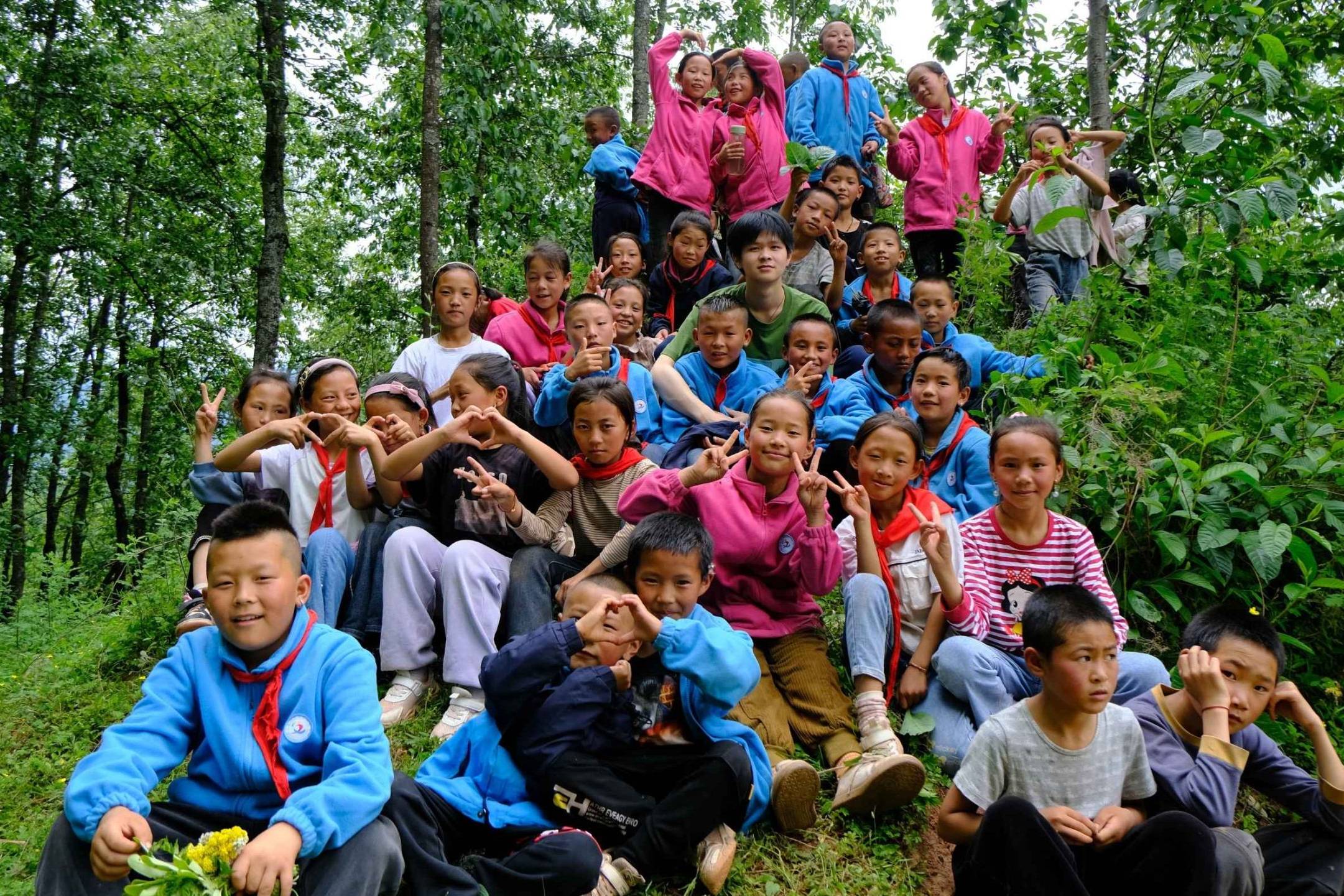 A group of children in colorful clothing pose playfully in a lush forest. The scene conveys joy and camaraderie among the vibrant greenery.