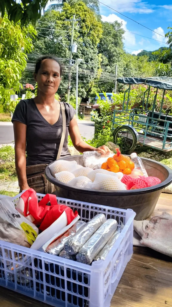 A woman poses in front of a table showcasing a basket brimming with food items.