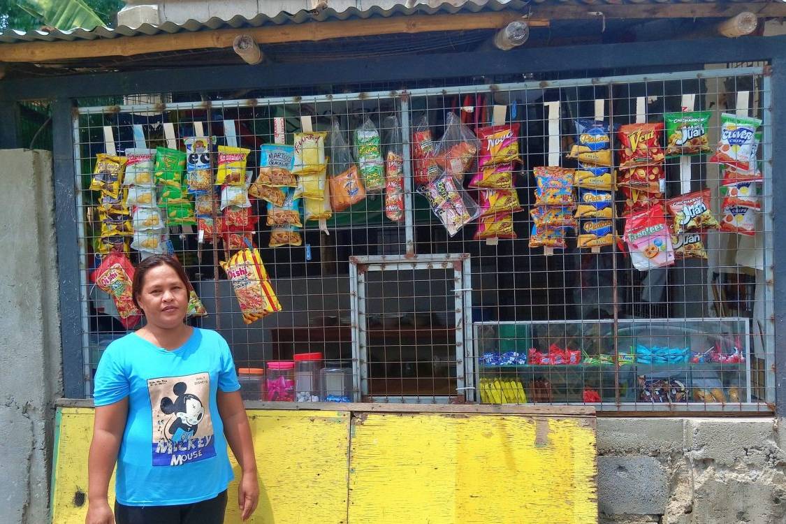 Woman stands in front of a small store