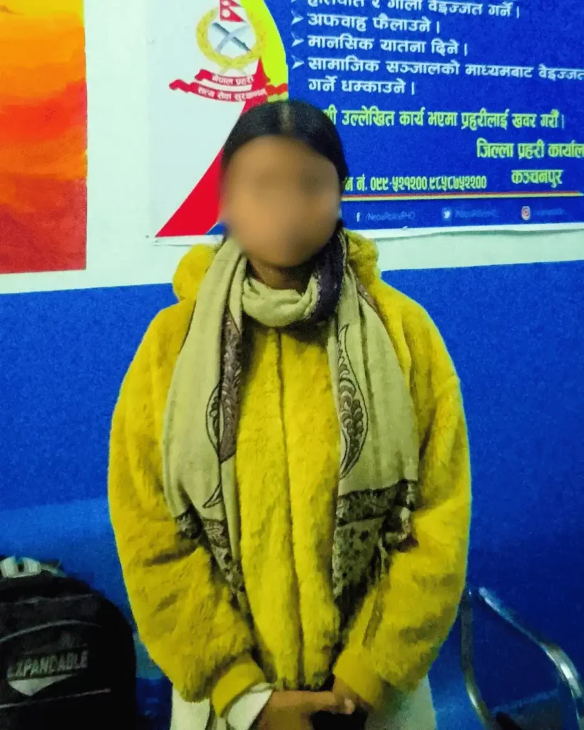 A young woman stands against a painted wall.