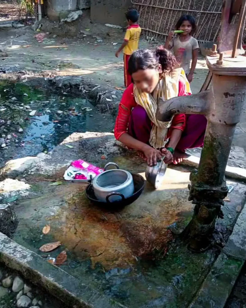 A woman cleans her pots in a water well, with nature around her and sunlight shining down.