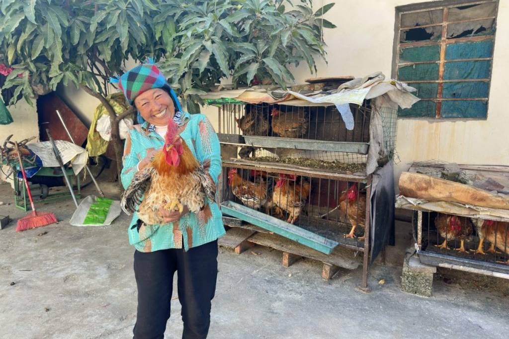 Woman Holds Up Chicken in her Chicken Farm