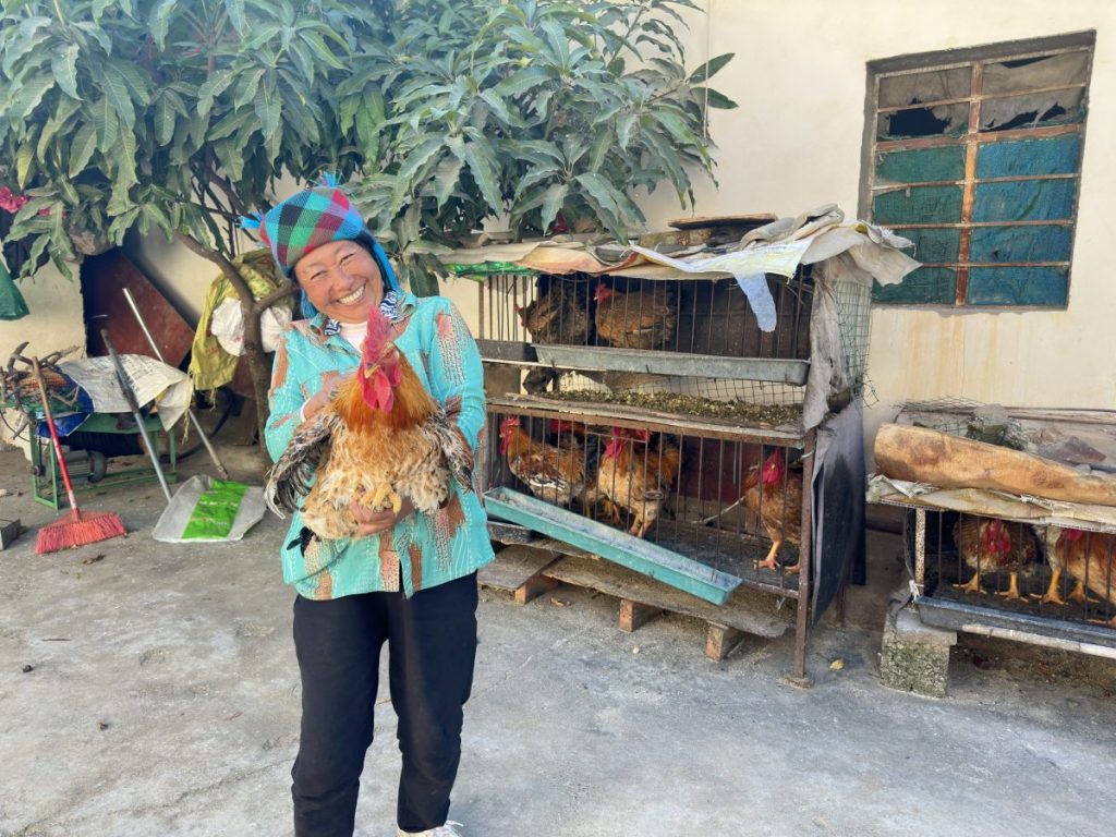 Woman Holds Up Chicken in her Chicken Farm