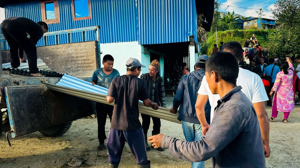 Local residents assist the response team in moving roofing sets for distribution.