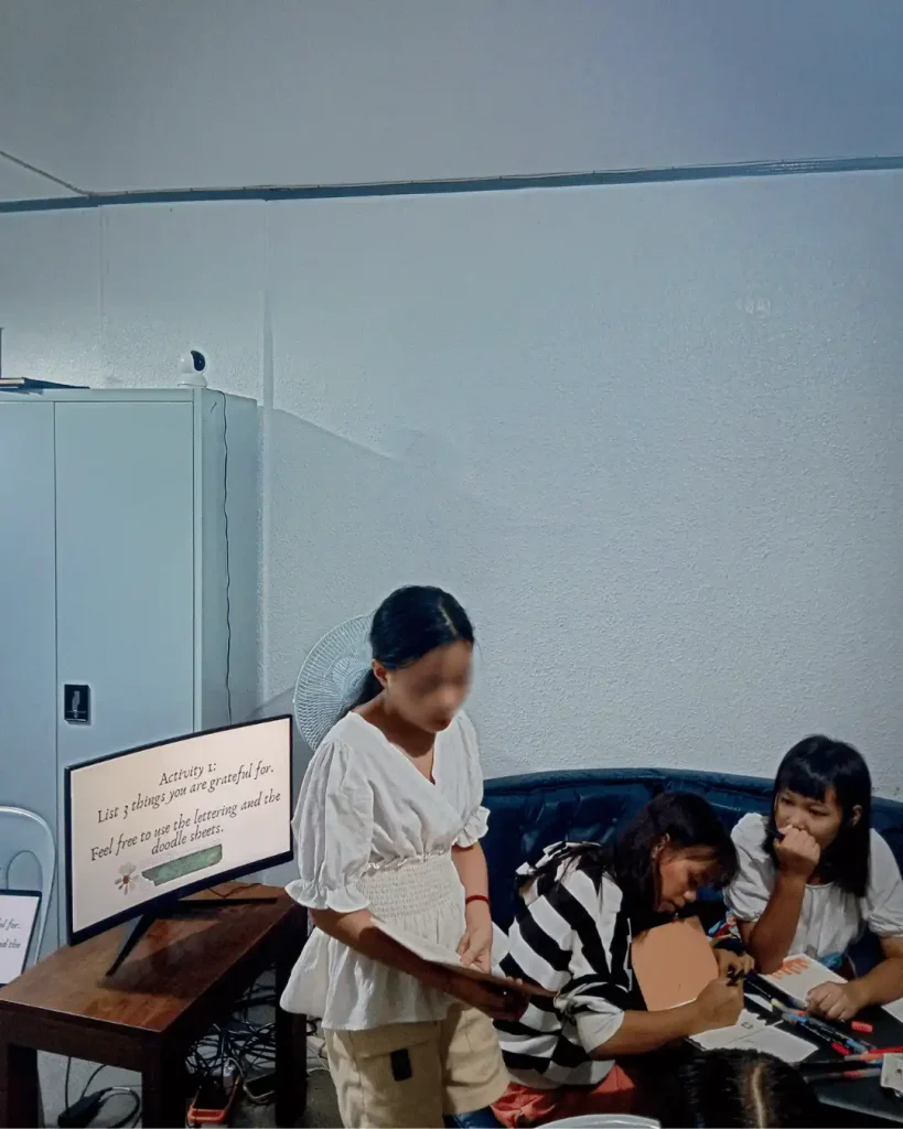 A gathering of young ladies around a table, participating in a discussion and sharing insights in a group setting.