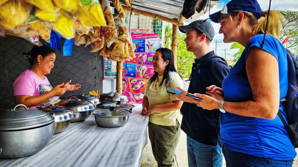A group of people gathered around a food stand, chatting.
