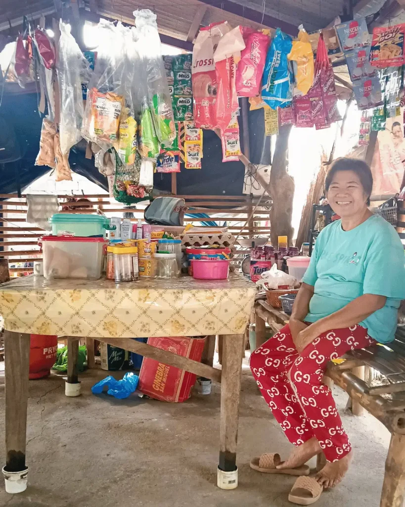 A woman sits in front of a table brimming with items
