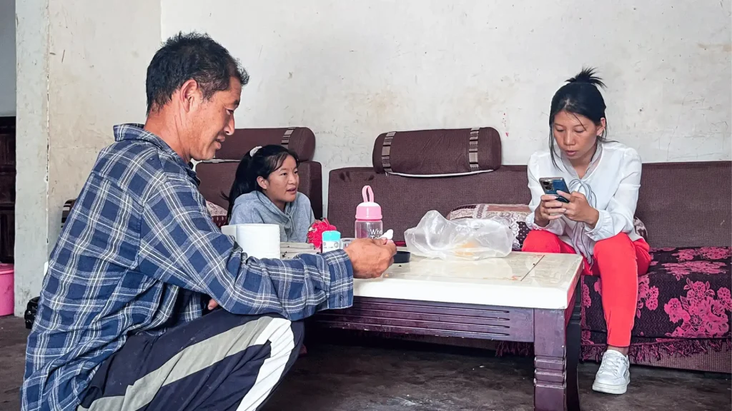 A man, a woman, and a child sit together on a couch, looking happy and engaged in conversation.