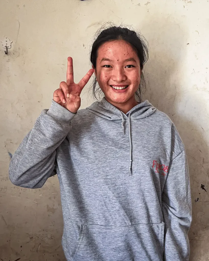 A young woman smiling and making a peace sign with her hands, conveying a message of positivity and harmony.