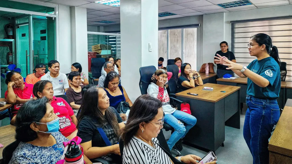 A woman addresses a group of people, sharing information during a formal presentation.