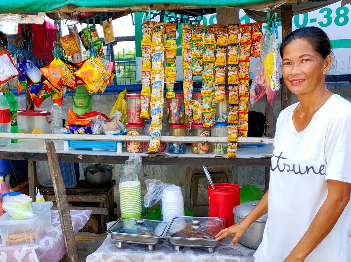 Filipina standing in front of her mini store.