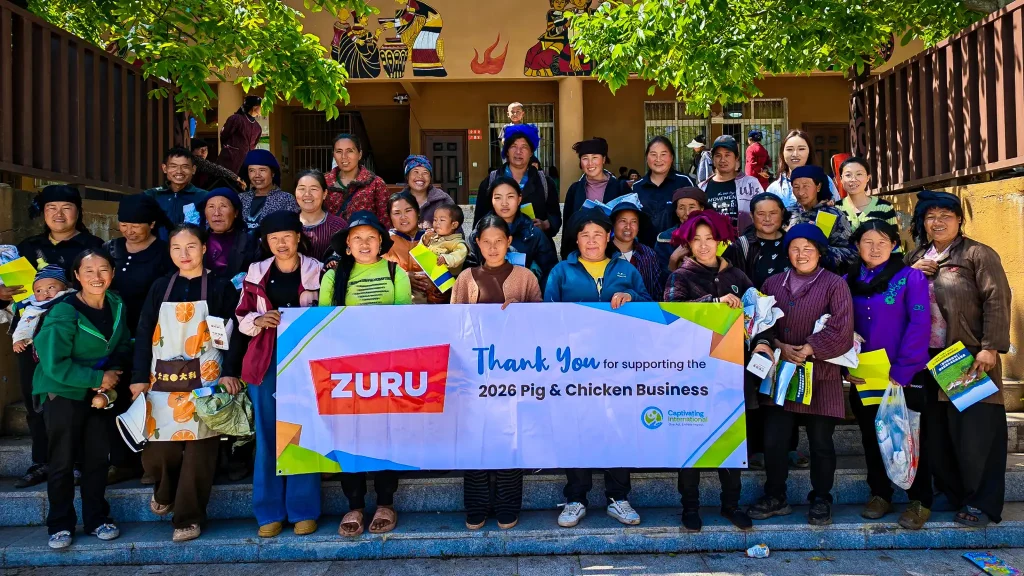 A diverse group of people poses for a photo, proudly displaying a sign that reads "Thank You" in a celebratory environment.