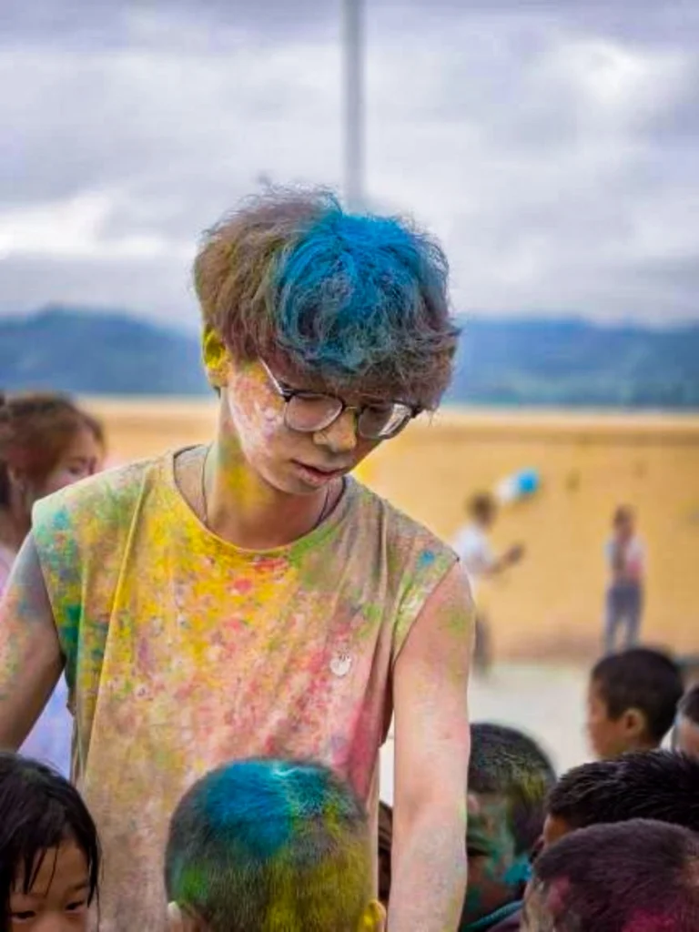 A man covered in colorful paint on his face and hands.