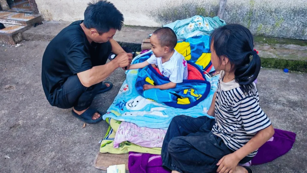A man and two kids are sitting on the ground