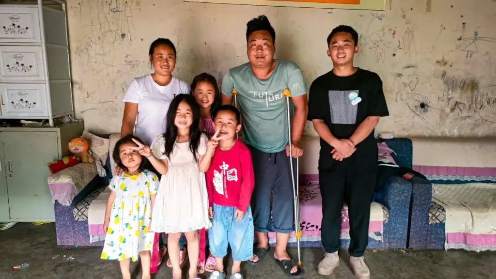 A family smiles together for a photo in a cozy room with a couch in the background.