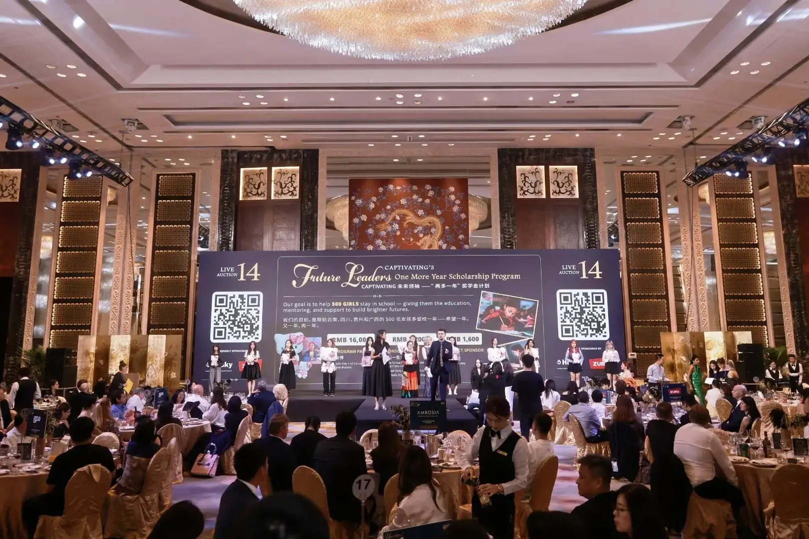 A gala event features a large stage with a banner for the Future Leaders scholarship program, with guests seated at round tables in a ballroom.
