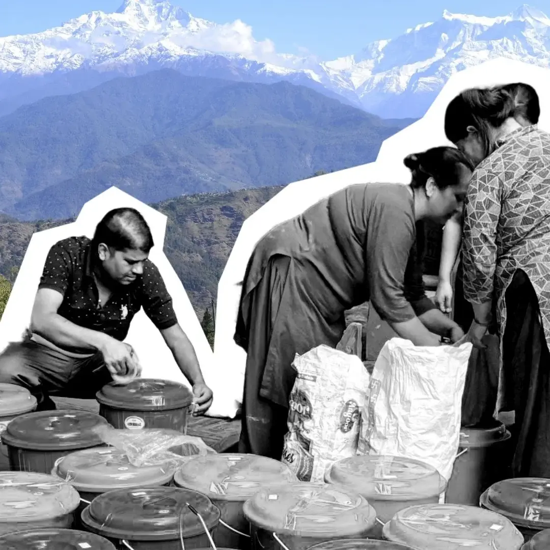 A man and two women work with many plastic containers and sacks against a backdrop of snow-capped mountain peaks in a bright, outdoor setting.
