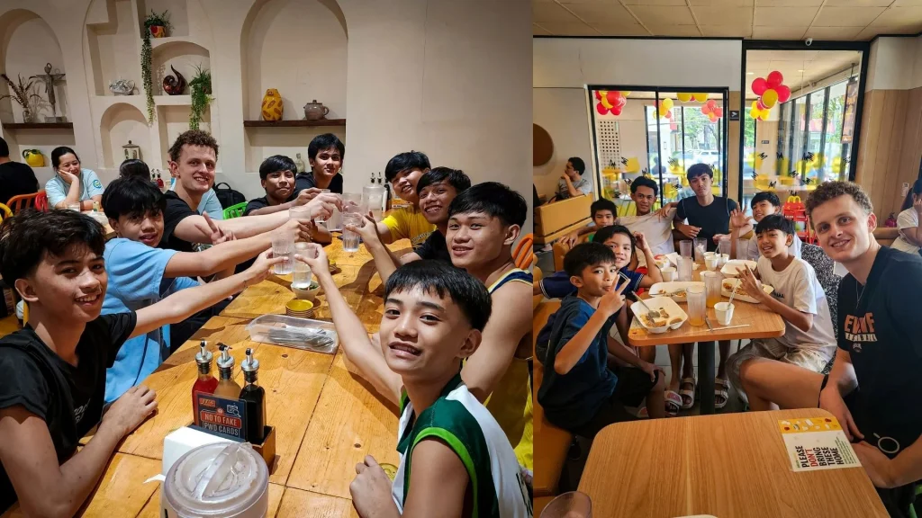 A cheerful group of friends raises drinks and smiles around restaurant tables, enjoying a lively meal together in a bright, welcoming setting in the Philippines.