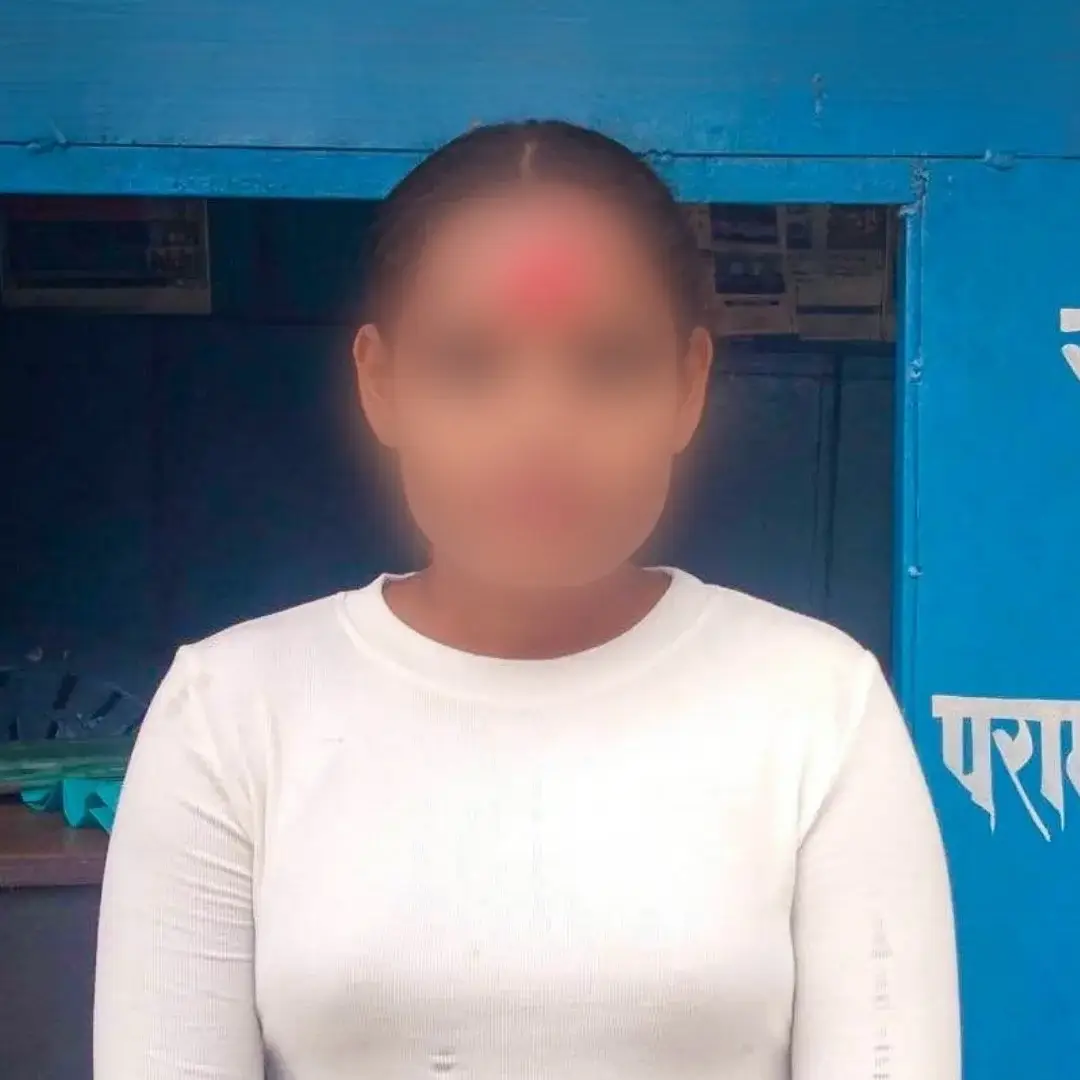 A blurred-faced person in a white long-sleeve shirt stands outside a bright blue Hindi-language information booth in Nepal, conveying a formal tone.