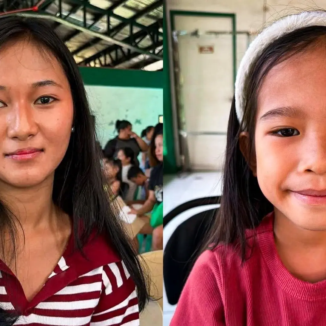 Two girls sit indoors in the Philippines; the left one wears a red and white striped shirt, while the right one wears a red top and white headband. Other people are visible in the background.